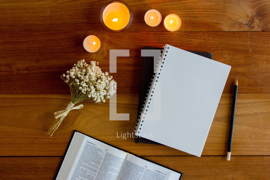 open Bible, journal, and candles on a wood background 