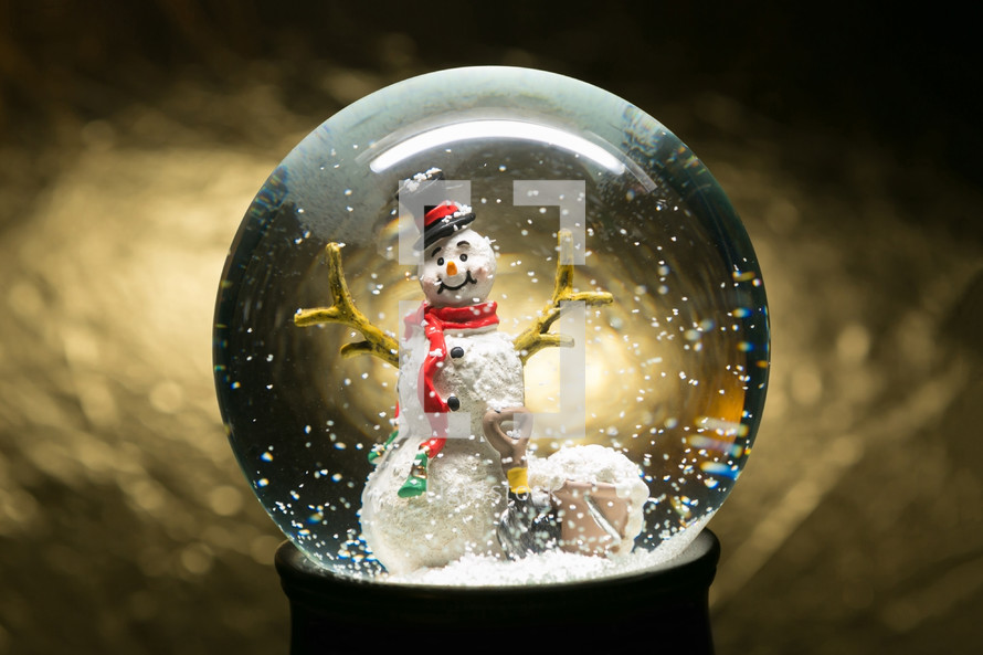a snowman in a snow globe against a gold background 