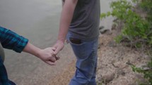 a couple walking holding hands by a pond 