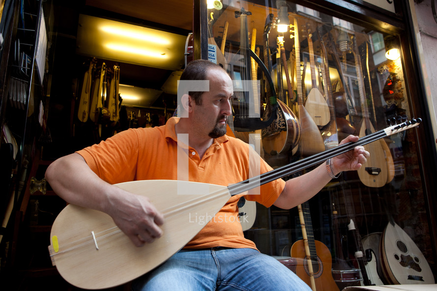 Turkish man playing Saz outside music store