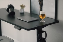 camera, laptop computer, and beer on a desk 