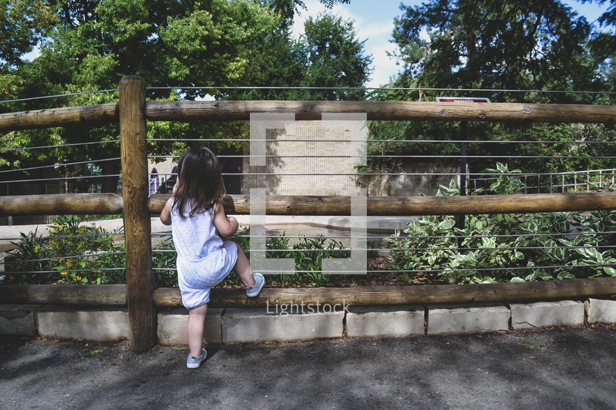 a girl looking through a fence 
