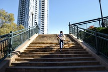 boy walking up outdoor steps in a city 