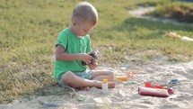 Boy plays sand toys outdoors. Little sweet boy playing in sandbox on playground. Child playing in the sandbox with toy. Happy family healthy children concept.