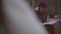 Woman Reading Bible Around Campfire with Small Group