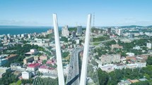 aerial view of a modern suspension bridge over a coastal city with a mix of urban and green landscapes 4k drone shot