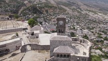 Aerial arc around clock tower of historic Gjirokaster castle atop hillside