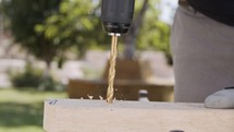 Close up of a drill making a hole in a piece of wood - slow motion