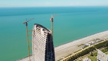 Cranes on the skyscraper construction by the sea