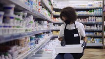 Female worker arranging products on shelves in milk department in supermarket, slow motion.