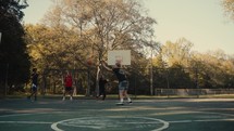 Young men playing basketball on an outdoor court on a sunny day