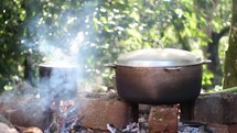 Cooking in cast iron pots over an outdoor fire.