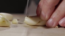 Slicing Garlic Cloves On a Chopping Board With A Knife. - close up shot