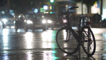 Cars with headlights on passing a bike in the rain