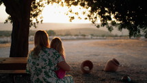 A mother holding her daughter at a picnic table