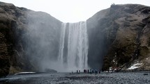 crowd of people standing in front of a waterfall 