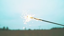 woman walking in a field carrying a sparkler 