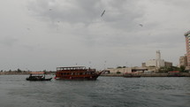 Boats and birds flying in cinematic slow motion at the Old Dubai river in middle eastern city.