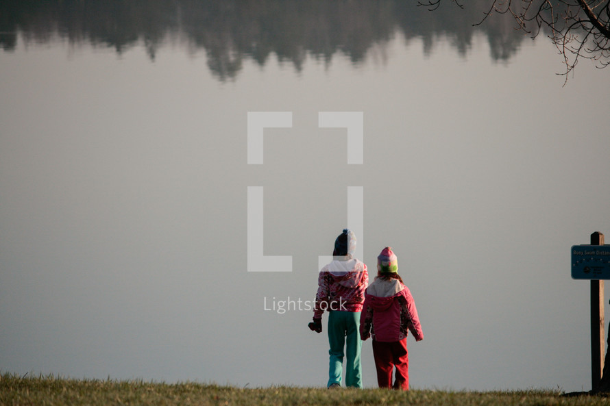 girls standing on a lake shore 