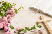 Bible, wood cross and spring blossoms on a white table with copy space