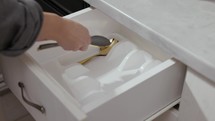 Cropped View Of A Person Arranging Tableware Inside The Drawer. Close-Up Shot