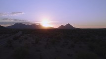 Aerial into the sunset over rugged desert mountains