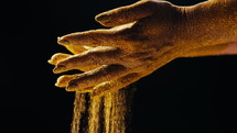 Golden glittering woman hands with dust or sand on black background. 