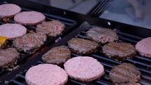 Flipping hamburgers on a grill at a large picnic