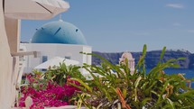 Panoramic view of Three Bells of Fira blue dommed church over caldera and vulcano island with anchored Cruiser ferry boats, Santorini, Greece