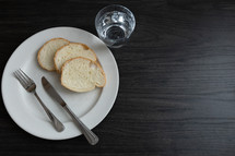Bread and water meal on a dark wood table