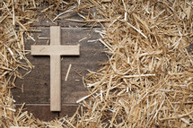 cross and hay on dark wood 
