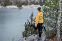 a woman and her dog looking out at a lake 