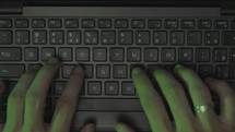 Top view shot closeup of man on desk writing on a laptop keyboard
