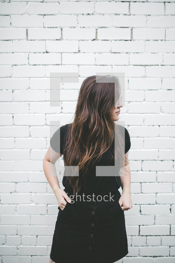 a woman standing in front of a white brick wall 