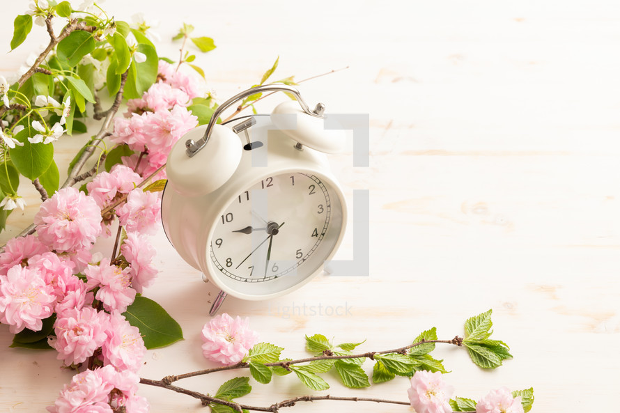 White alarm clock with pink flowers on a white background