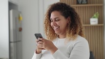 Happy black woman holding cell phone using smartphone device at home. 