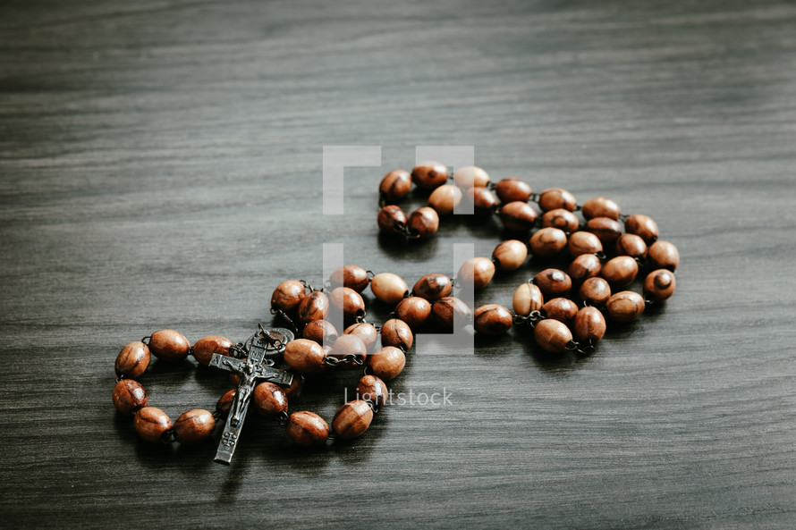 Wood rosary on a dark wood background with copy space