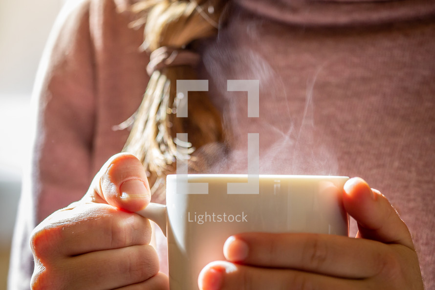 a woman holding a steaming coffee mug