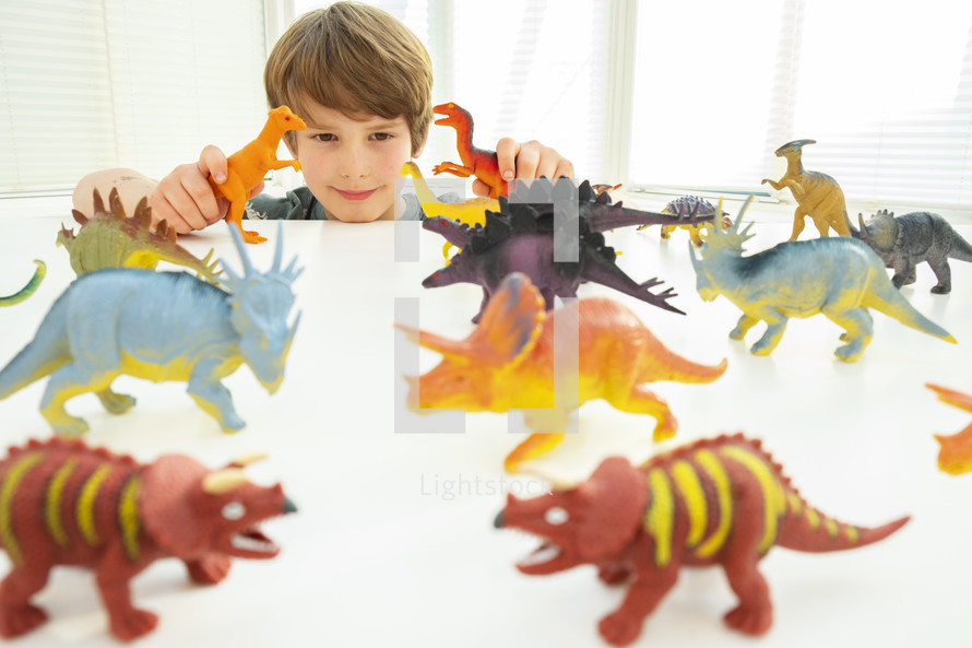 Caucasian boy playing with toy dinosaurs