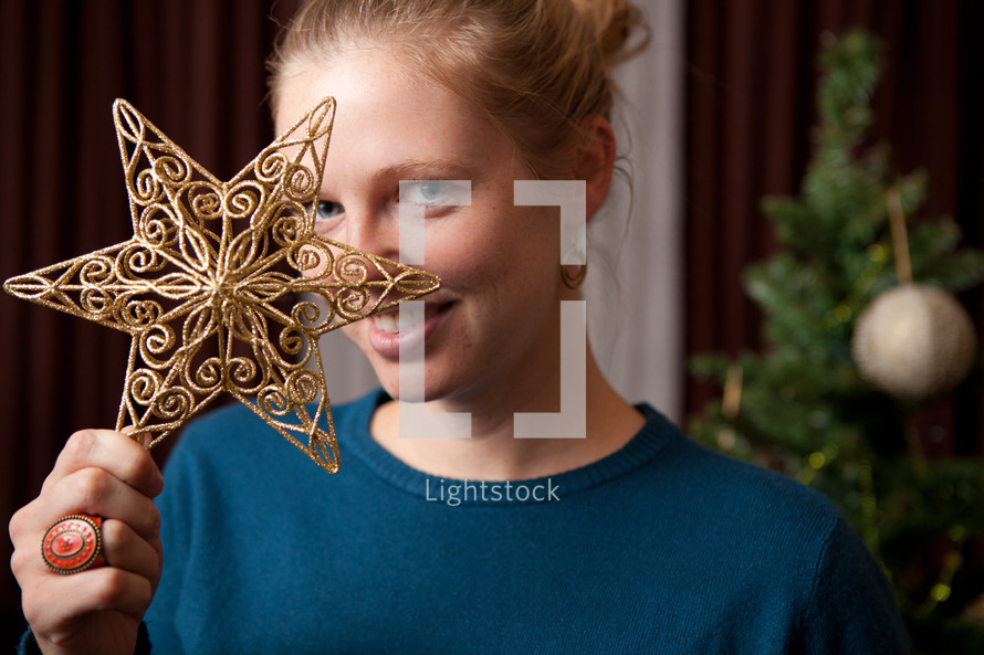 woman holding a star ornament in front of her face