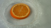 an orange slice falling into water 