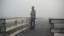 man walking on a boardwalk on a foggy morning 