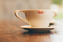 A cup and saucer with a lipstick mark.