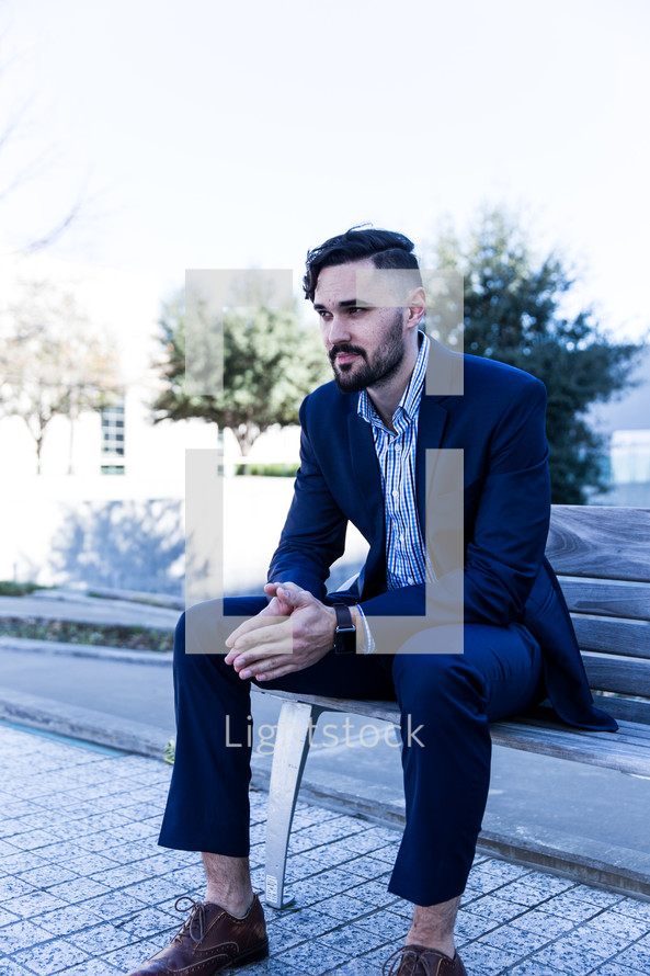 man in a suit sitting on a bench 