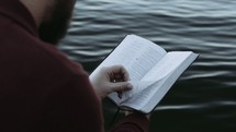a man reading a Bible over water 