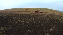 Aerial drone forward shot of a traktor working on the hill