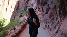 Caucasian woman hiking on trail path in Zion national park with rock formations. Picturesque driftwood and red sand