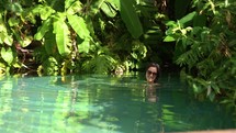 Young woman swimming in natural tropical pool.