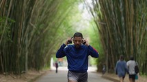 Young sporty black man runner, morning run in the city urban park Running outdoors healthy active sport lifestyle. fitness  man jogging. listens to music or a podcast in headphones
