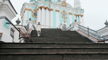Woman in warm coat in Kyiv street. Walking down old stone stairs near Cathedral. 
 Lifestyle concept. Young girl in European city, winter or autumn time.